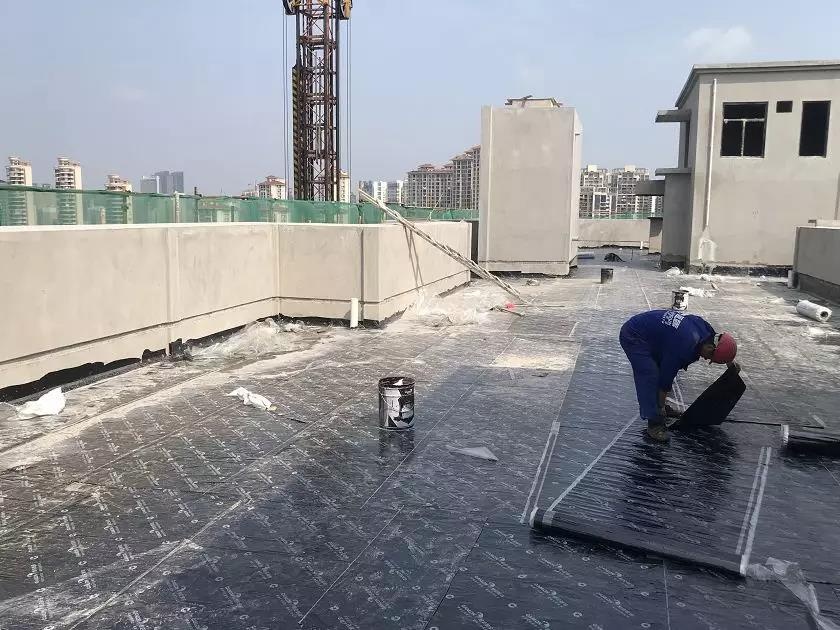 施工工人顶着炎热正做楼顶防水工作